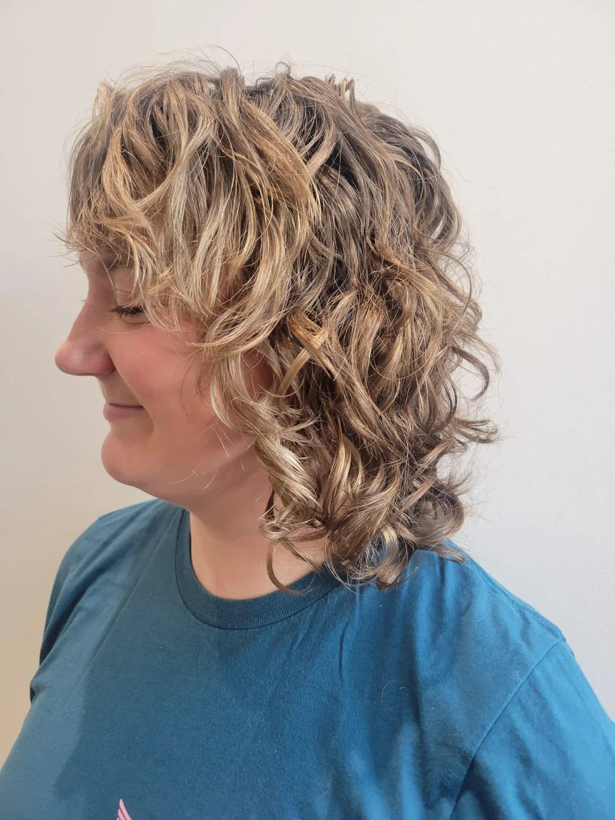 Blonde highlighted curly bob from the side